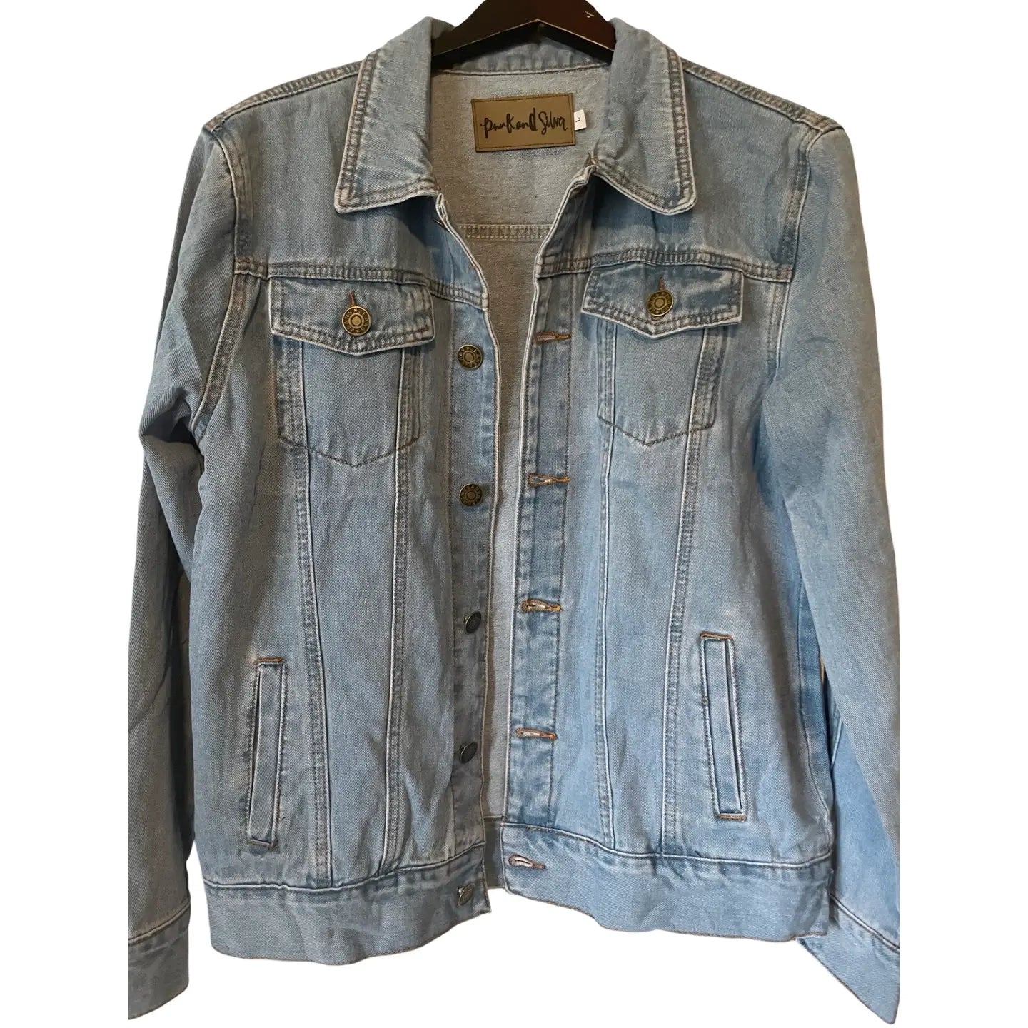 Denim jacket on a hanger with a visible brand label against a white background