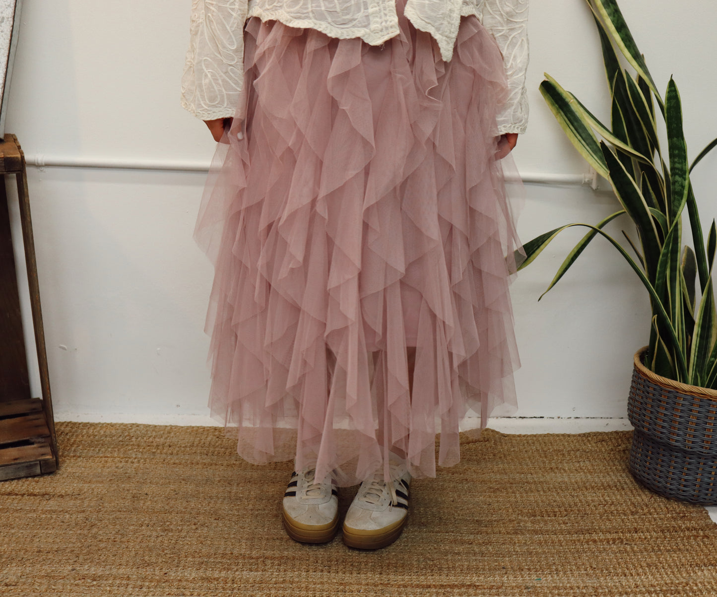 Person wearing a layered pink skirt with white lace top, standing on a woven mat.