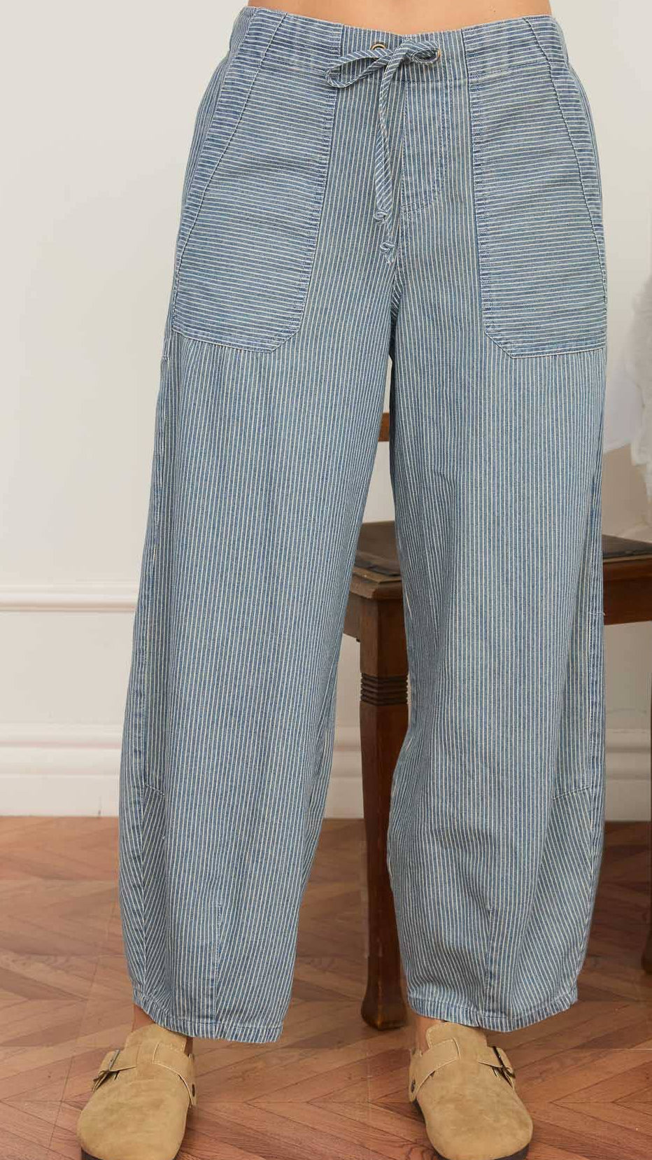 Blue striped pants worn by a person on a wooden floor.