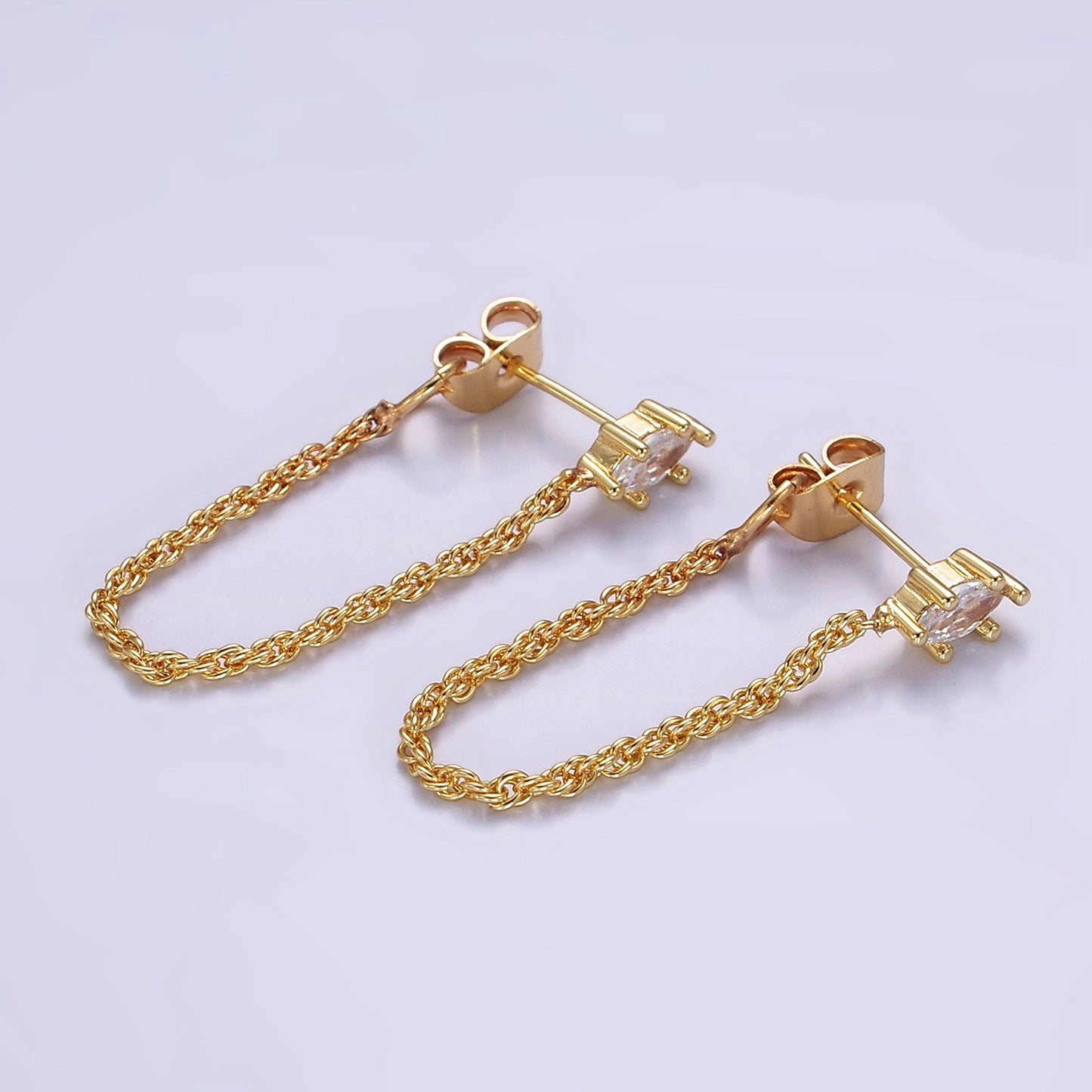 Gold chain earrings on a light purple background