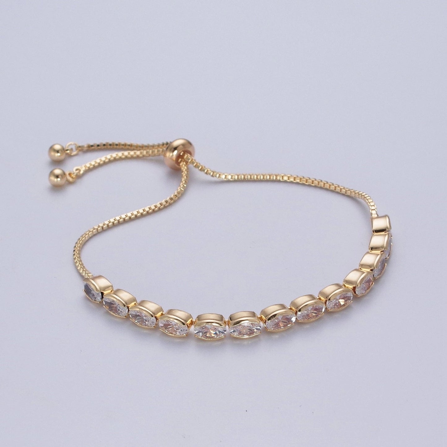 Gold bracelet with clear stones on a light gray background