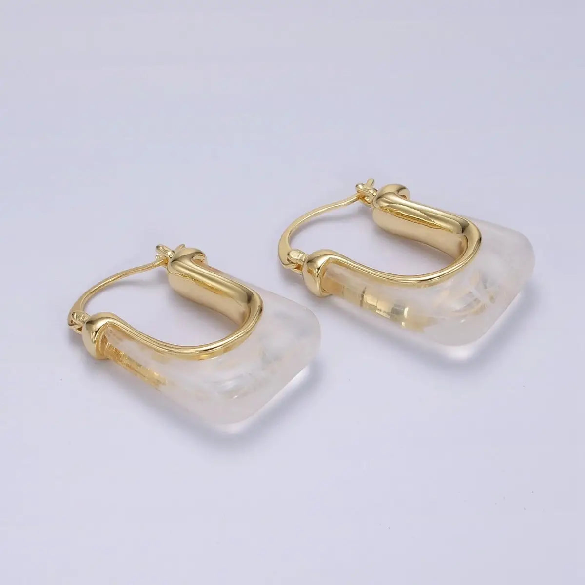 Gold hoop earrings with clear stone accents on a light gray background